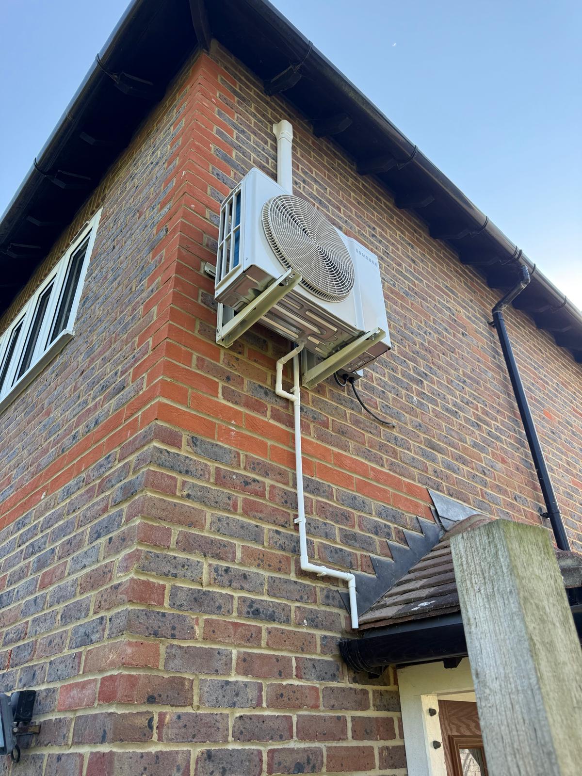 Outdoor condenser unit mounted on a brick wall awaiting repair